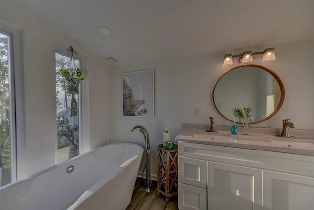 bathroom with vanity, a bath, and wood-type flooring