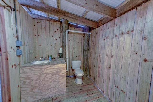 bathroom with hardwood / wood-style flooring, vanity, wooden walls, and toilet