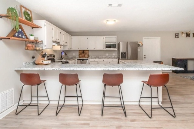 11525 Lott Rd, Chunchula, AL 36521 - kitchen featuring stainless steel appliances, a peninsula, under cabinet range hood, a kitchen bar, and light wood-style floors