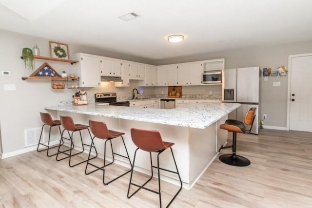 11525 Lott Rd, Chunchula, AL 36521 - kitchen with stainless steel appliances, under cabinet range hood, a peninsula, light wood-style flooring, and open shelves