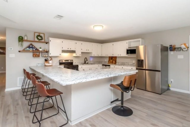 11525 Lott Rd, Chunchula, AL 36521 - kitchen featuring stainless steel appliances, a peninsula, light wood finished floors, and white cabinets