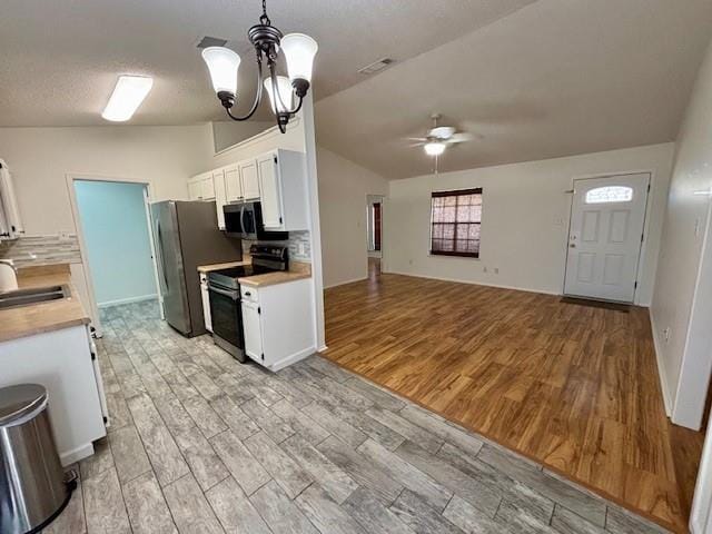 kitchen with ceiling fan with notable chandelier, white cabinetry, hanging light fixtures, stainless steel appliances, and light wood-type flooring