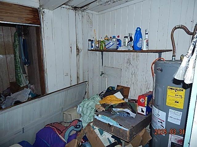 interior space with water heater and wood walls