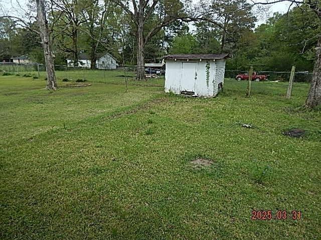 view of yard with fence, an outdoor structure, and a shed