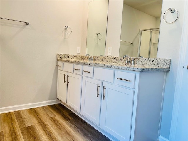 bathroom with hardwood / wood-style flooring, vanity, and a shower with door