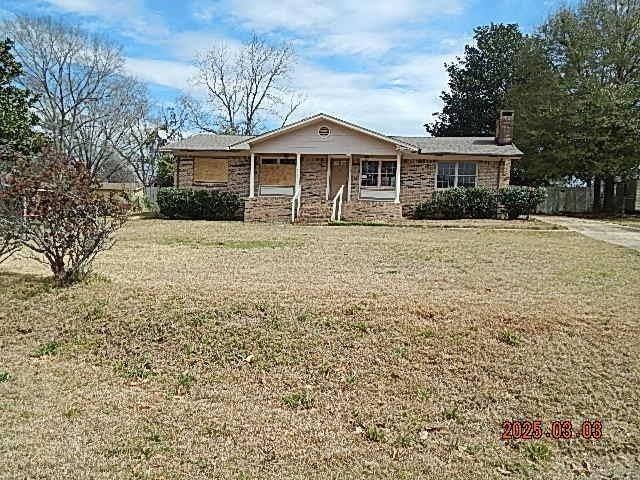 single story home with a chimney and a front yard