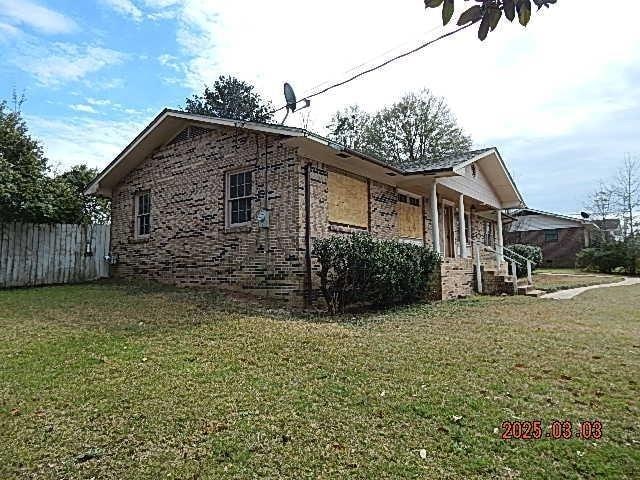 view of home's exterior featuring fence, a lawn, and brick siding