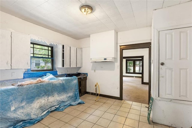672 Burden St, Mobile, AL 36607 - kitchen featuring healthy amount of natural light, light tile patterned flooring, white cabinets, and baseboards