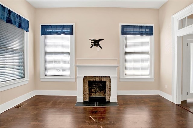 unfurnished living room featuring a healthy amount of sunlight and dark hardwood / wood-style flooring