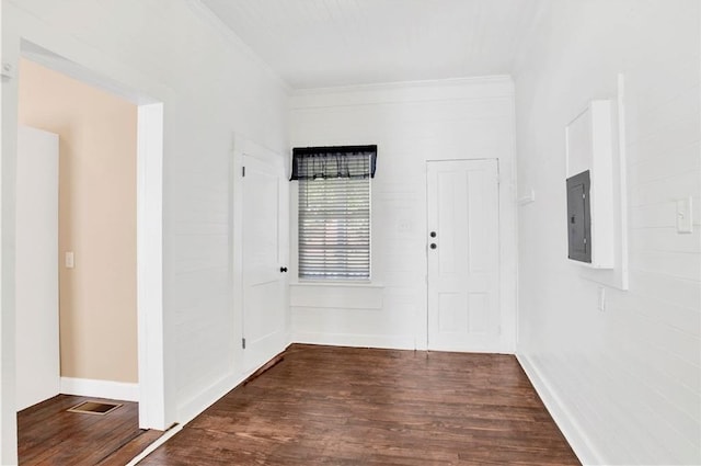 spare room with dark wood-type flooring, ornamental molding, and electric panel