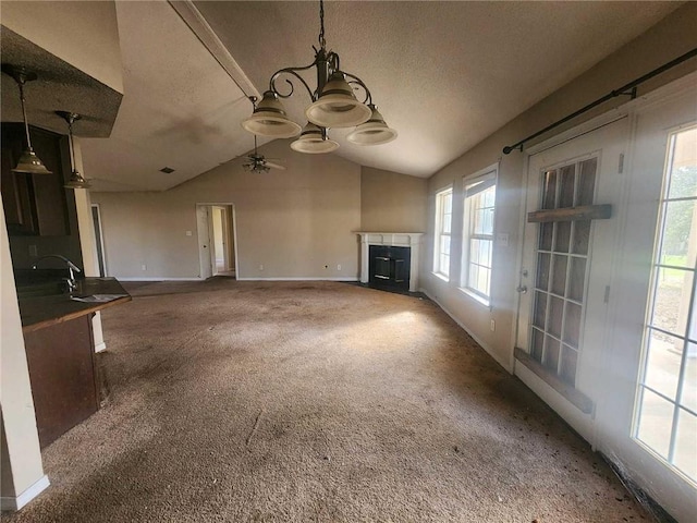 unfurnished living room featuring a fireplace, carpet flooring, vaulted ceiling, ceiling fan, and baseboards