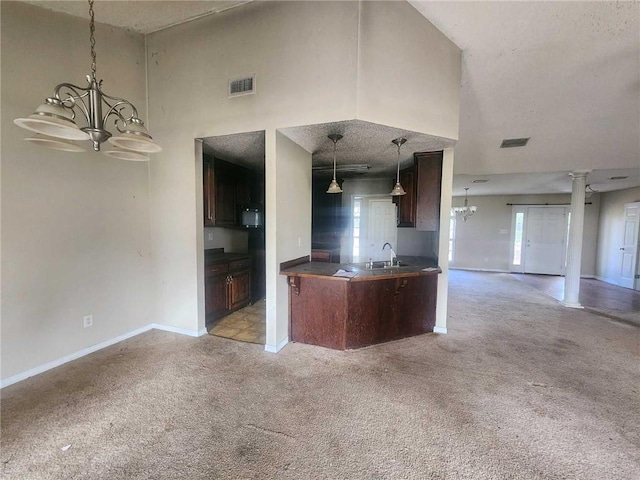 kitchen with a notable chandelier, dark countertops, visible vents, open floor plan, and light carpet