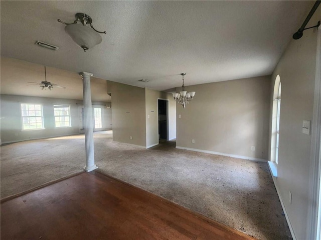 empty room featuring baseboards, visible vents, a textured ceiling, ornate columns, and ceiling fan with notable chandelier