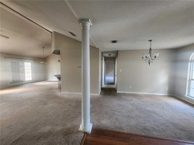 spare room with ornate columns, carpet, visible vents, and a notable chandelier