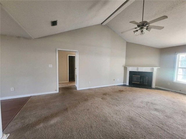 unfurnished living room featuring a tile fireplace, vaulted ceiling with beams, a textured ceiling, and carpet