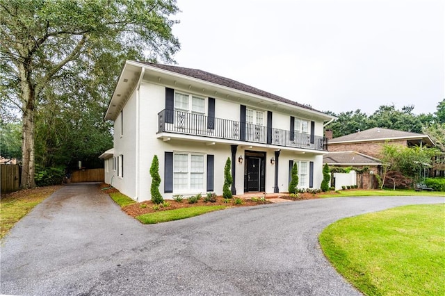 view of front of house featuring a balcony and a front lawn