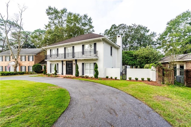 view of front of property featuring a balcony and a front lawn