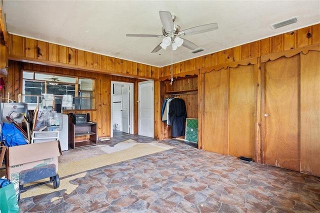 interior space featuring ceiling fan and wood walls