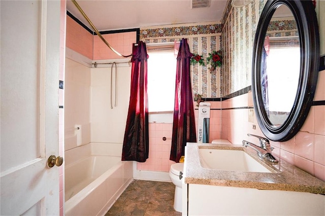 full bathroom featuring vanity, tile walls, shower / bath combo with shower curtain, and toilet