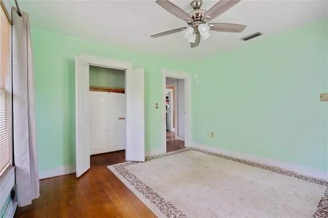 unfurnished bedroom featuring ceiling fan, dark wood-type flooring, and a closet