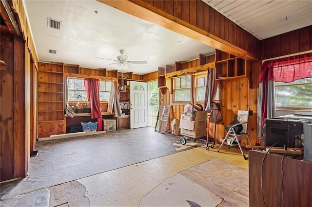 miscellaneous room with wooden walls, ceiling fan, and plenty of natural light