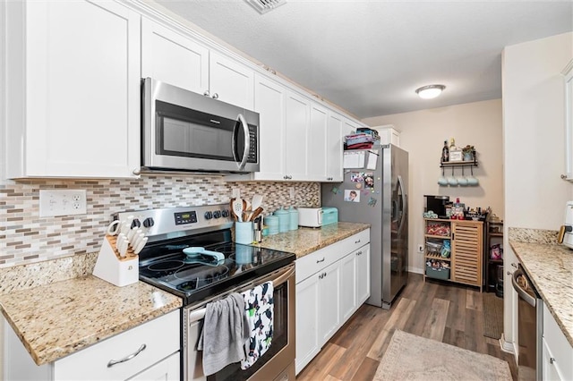 kitchen featuring light stone counters, appliances with stainless steel finishes, tasteful backsplash, and white cabinets