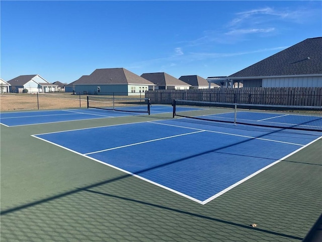 view of tennis court with a residential view and fence