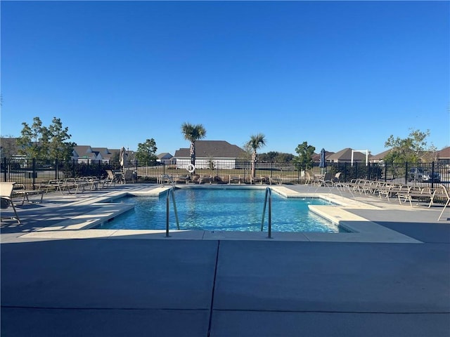 community pool with a patio area and fence