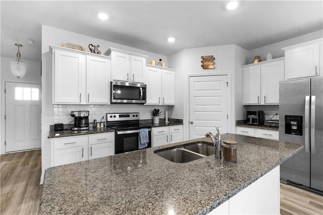 kitchen with decorative backsplash, light wood-style flooring, stainless steel appliances, white cabinetry, and a sink