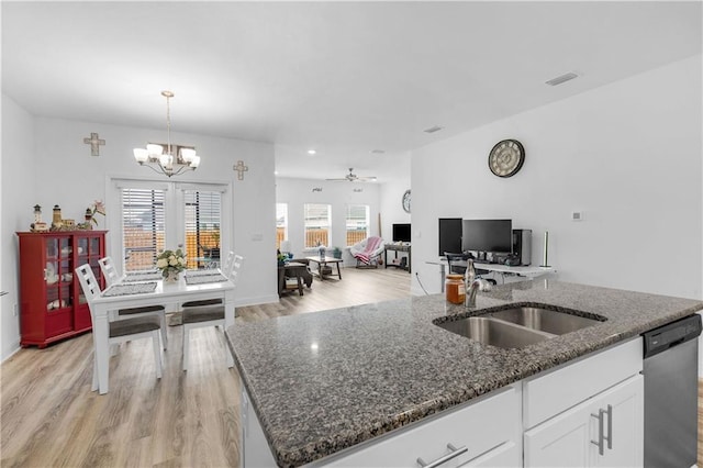 kitchen with visible vents, a sink, light wood-style flooring, stainless steel dishwasher, and a kitchen island with sink