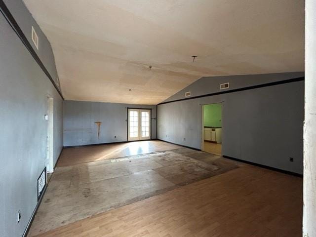 spare room featuring wood-type flooring, french doors, and lofted ceiling