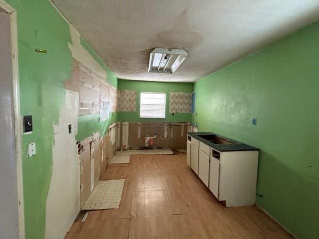 kitchen featuring white cabinets, light hardwood / wood-style floors, and a textured ceiling