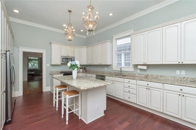 kitchen featuring ornamental molding, a center island, an inviting chandelier, dark hardwood / wood-style floors, and appliances with stainless steel finishes