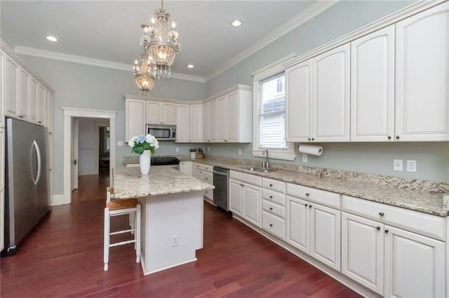 kitchen with a kitchen island, dark wood-type flooring, stainless steel appliances, and ornamental molding