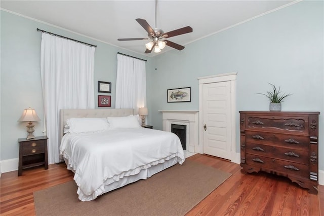 bedroom with wood-type flooring, crown molding, and ceiling fan