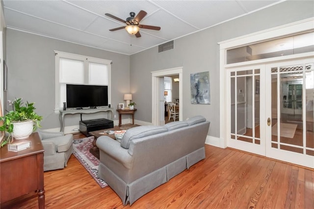 living room with french doors, ceiling fan, and light wood-type flooring