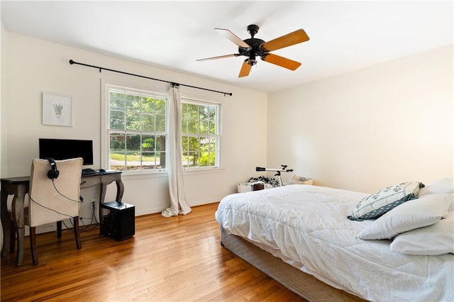 bedroom with light wood-style flooring, baseboards, and a ceiling fan