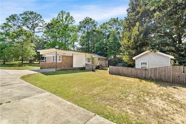 exterior space featuring concrete driveway, brick siding, a front yard, and fence