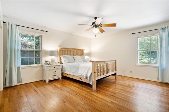 bedroom with light wood-style floors, multiple windows, and baseboards