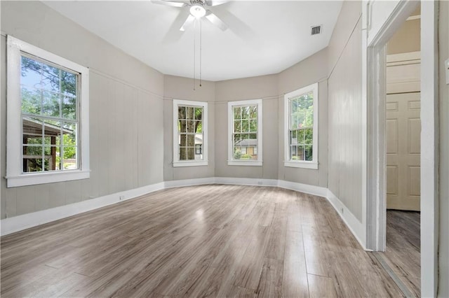 spare room with ceiling fan, a wealth of natural light, and light hardwood / wood-style flooring