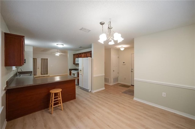 kitchen featuring sink, white appliances, light hardwood / wood-style flooring, decorative light fixtures, and kitchen peninsula