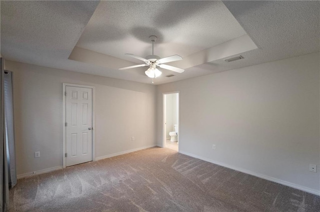 carpeted spare room with ceiling fan, a tray ceiling, and a textured ceiling