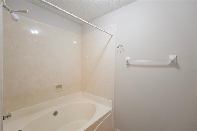 bathroom featuring bathtub / shower combination and a textured ceiling