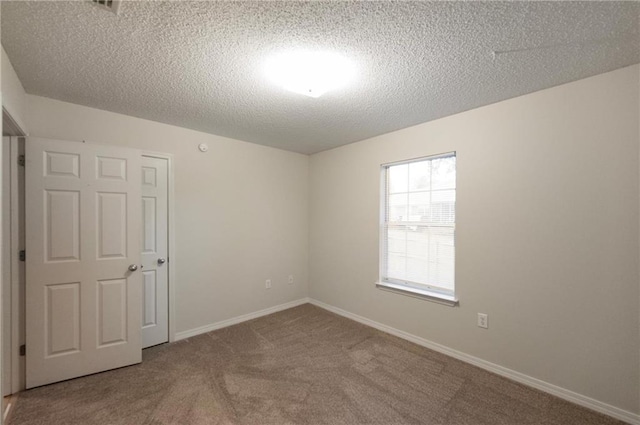 carpeted empty room with a textured ceiling