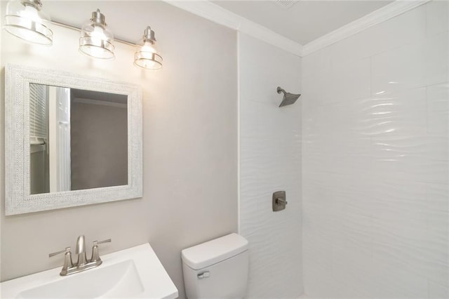 bathroom with vanity, toilet, crown molding, and a tile shower