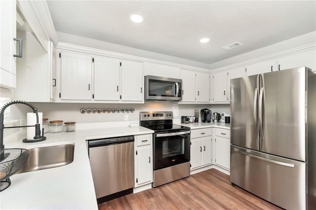 3132 Wellborne Dr W, Mobile, AL 36695 - kitchen featuring appliances with stainless steel finishes, light countertops, white cabinetry, wood finished floors, and recessed lighting