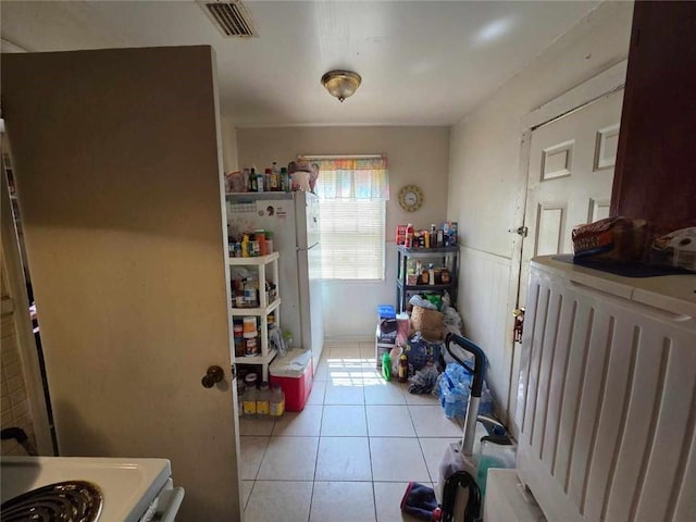 kitchen with light tile patterned floors, stove, and freestanding refrigerator