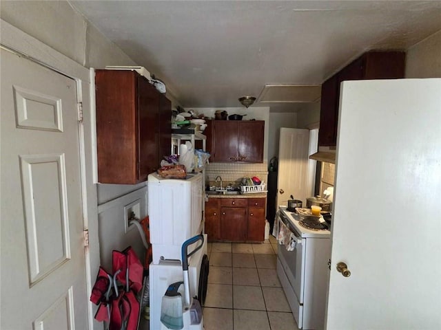 kitchen featuring white appliances, under cabinet range hood, light tile patterned floors, backsplash, and light countertops