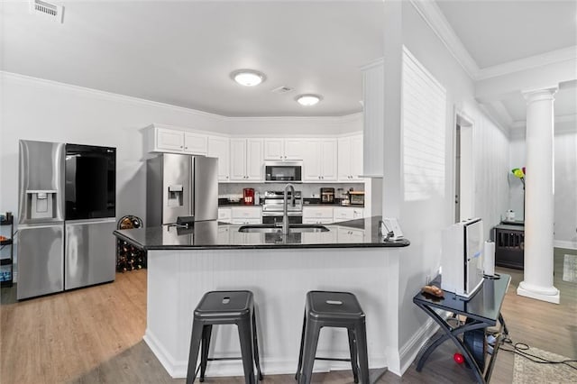 kitchen featuring kitchen peninsula, ornamental molding, stainless steel appliances, sink, and white cabinetry