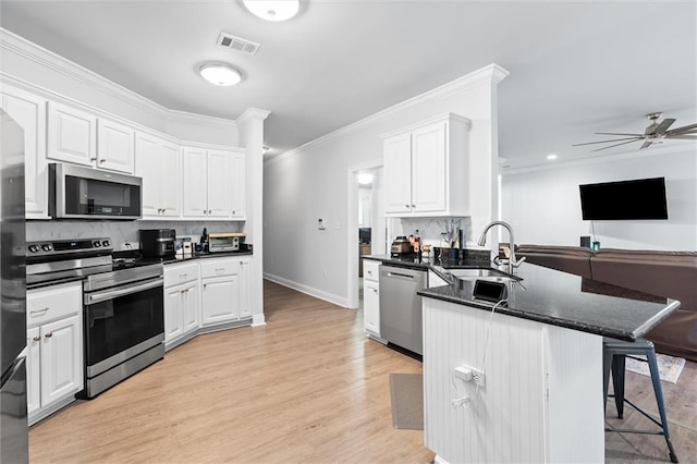 kitchen with white cabinetry, sink, stainless steel appliances, tasteful backsplash, and kitchen peninsula